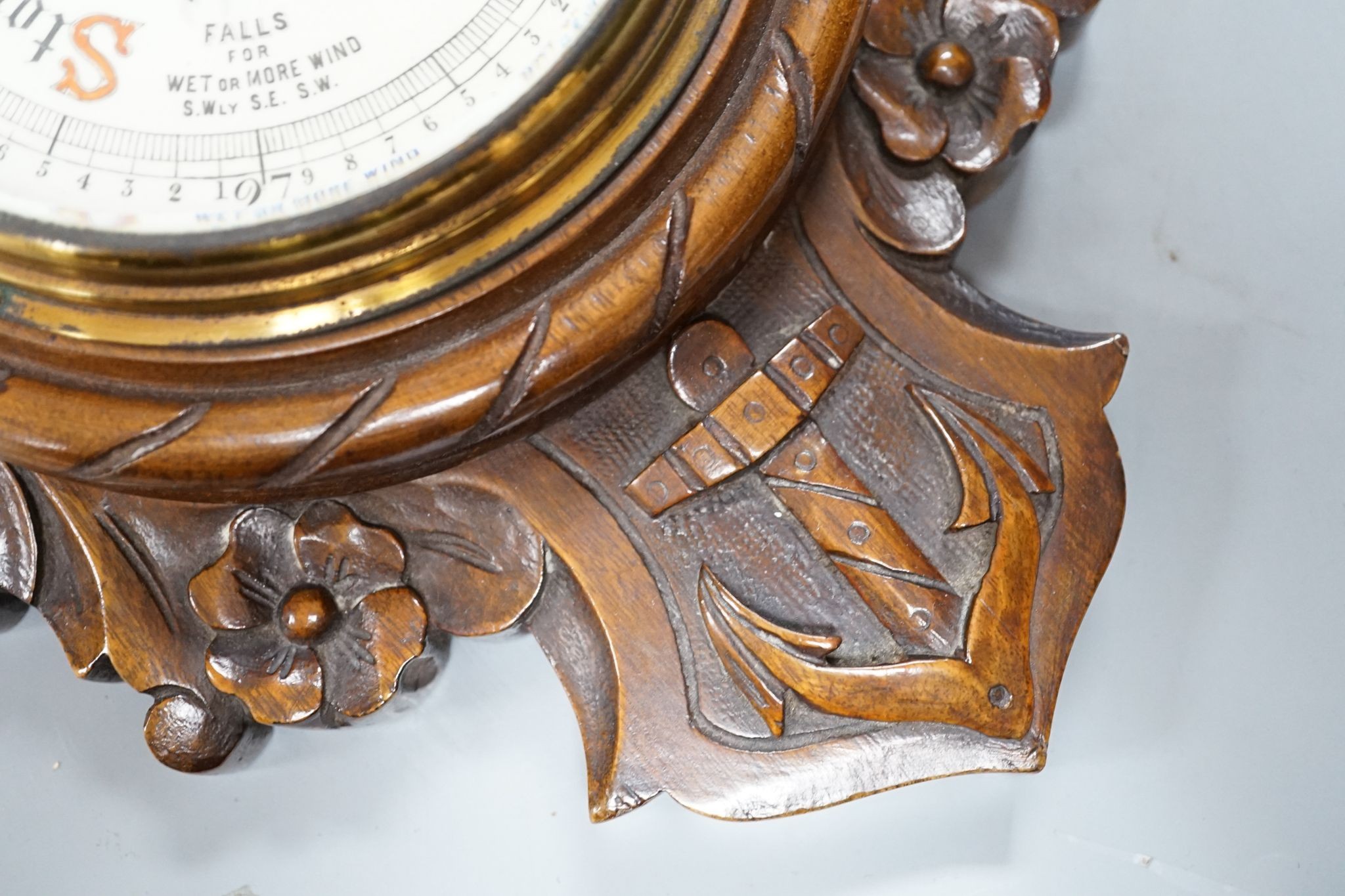 A Victorian carved walnut aneroid barometer with timepiece